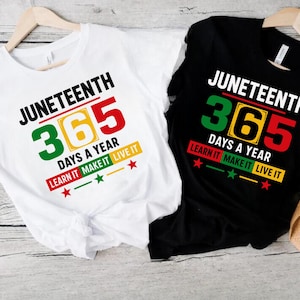 Peut inclure: Deux t-shirts avec le texte "Juneteenth 365 Days a Year Learn It Make It Live It" imprimé dessus. Les t-shirts sont blancs et noirs avec des accents rouges, jaunes et verts.