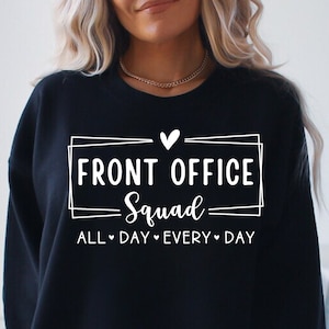 Peut inclure: Sweat-shirt noir avec un texte blanc qui dit "Front Office Squad All Day Every Day" avec un symbole de cœur entre les mots "All" et "Day" et entre les mots "Every" et "Day".