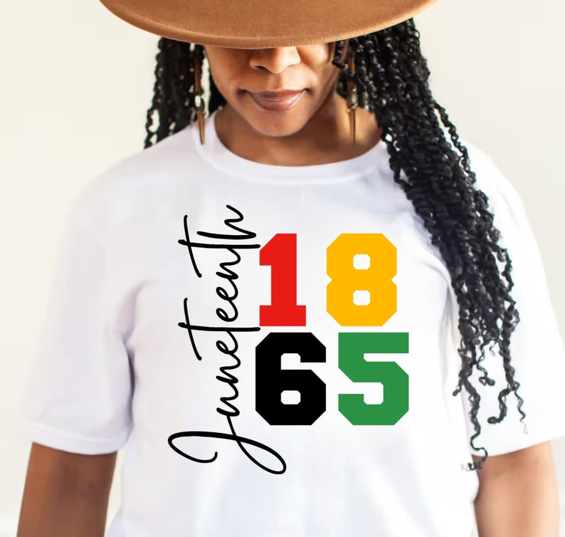 May include: White t-shirt with the text "Juneteenth 1865" in black, red, yellow, and green lettering.