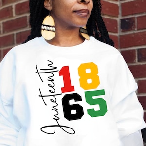 May include: White sweatshirt with the text "Juneteenth 1865" in black, red, yellow, and green lettering.
