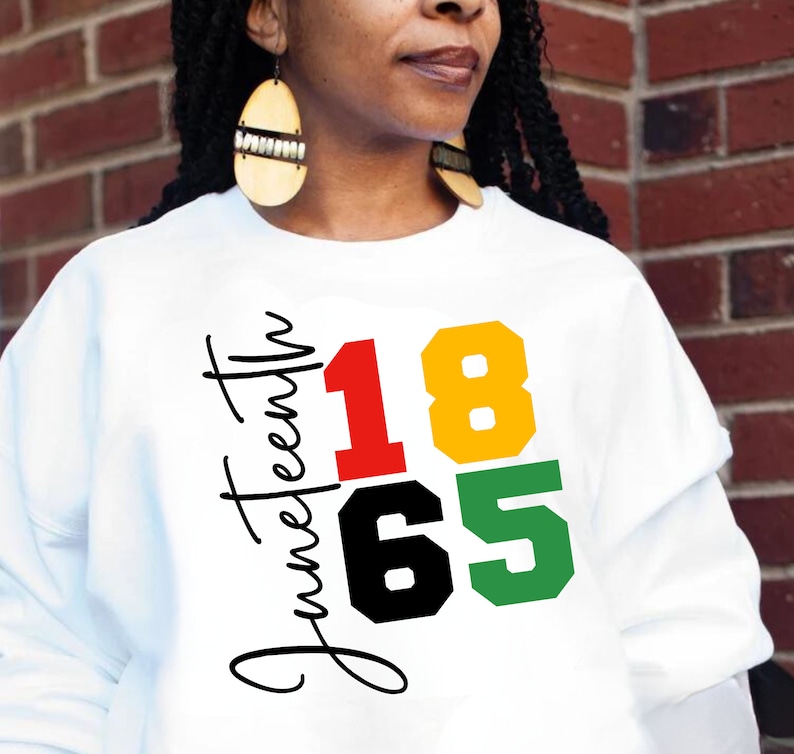 May include: White sweatshirt with the text "Juneteenth 1865" in black, red, yellow, and green lettering.