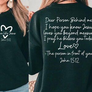 May include: Black sweatshirt with white text that reads "Love like Jesus" with a heart symbol and "John 15:12" on the front. The back of the sweatshirt reads "Dear Person Behind me, I hope you know Jesus loves you beyond measure I pray he blesses you today Love♡ -The person in front of you John 15:12"