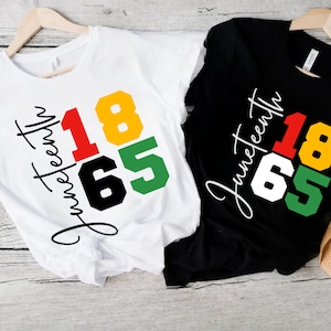 May include: Two t-shirts with the text "Juneteenth 1865" in black, red, yellow, and green. The text is in a block style font and the shirts are white and black.