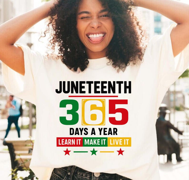 May include: White t-shirt with the text "Juneteenth 365 Days a Year Learn It Make It Live It" in black and green, red, and yellow lettering. There are three red stars below the text.