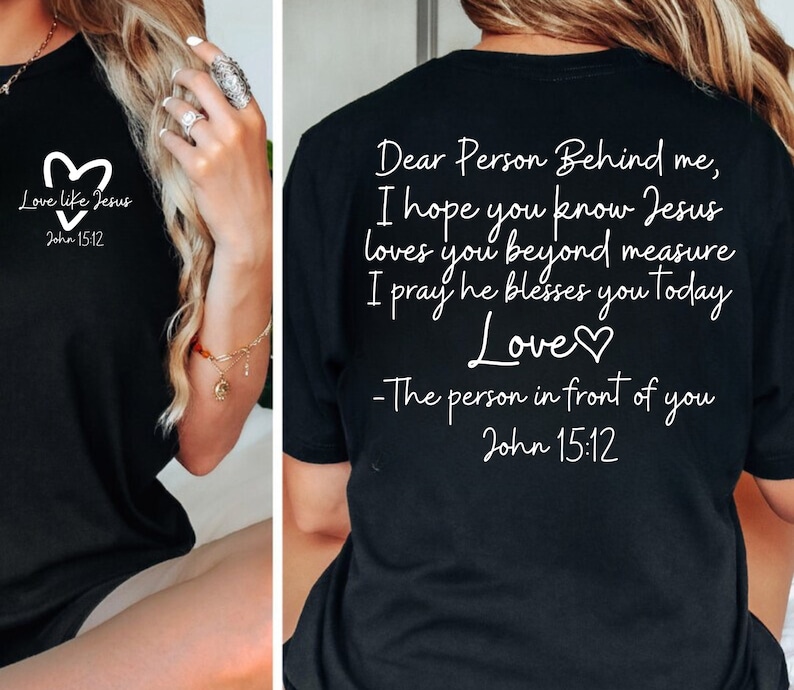 May include: Black t-shirt with white text that reads "Love like Jesus John 15:12" on the front and "Dear Person Behind me, I hope you know Jesus loves you beyond measure I pray he blesses you today Love♡ -The person in front of you John 15:12" on the back.