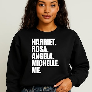 May include: Black sweatshirt with white text that reads "HARRIET. ROSA. ANGELA. MICHELLE. ME."