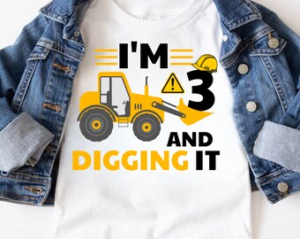 May include: A white t-shirt with a yellow construction vehicle and the text "I'm 3 and digging it".