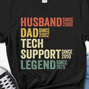 May include: Black t-shirt with a vintage-style graphic that reads "Husband since 2000, Dad since 2002, Tech Support since 2010, Legend since 1975".