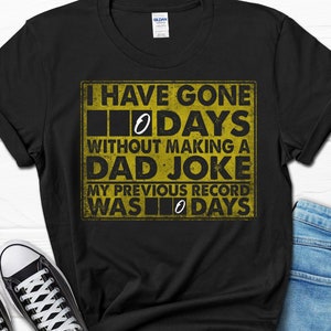 May include: Black t-shirt with a yellow graphic that says "I have gone 0 days without making a dad joke. My previous record was 0 days."