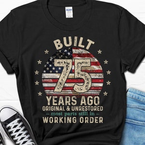 May include: Black t-shirt with a vintage American flag design and the text "Built 75 Years Ago Original & Unrestored - Most parts still in - Working Order".