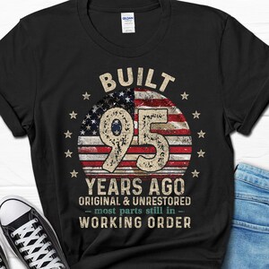 May include: Black t-shirt with a vintage American flag design and the text "Built 95 Years Ago Original & Unrestored - most parts still in - Working Order".