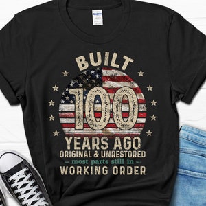 May include: Black t-shirt with a vintage American flag design and the text "Built 100 Years Ago Original & Unrestored - most parts still in - Working Order".