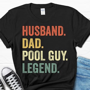 May include: Black t-shirt with a vintage-style graphic that reads "Husband. Dad. Pool Guy. Legend."