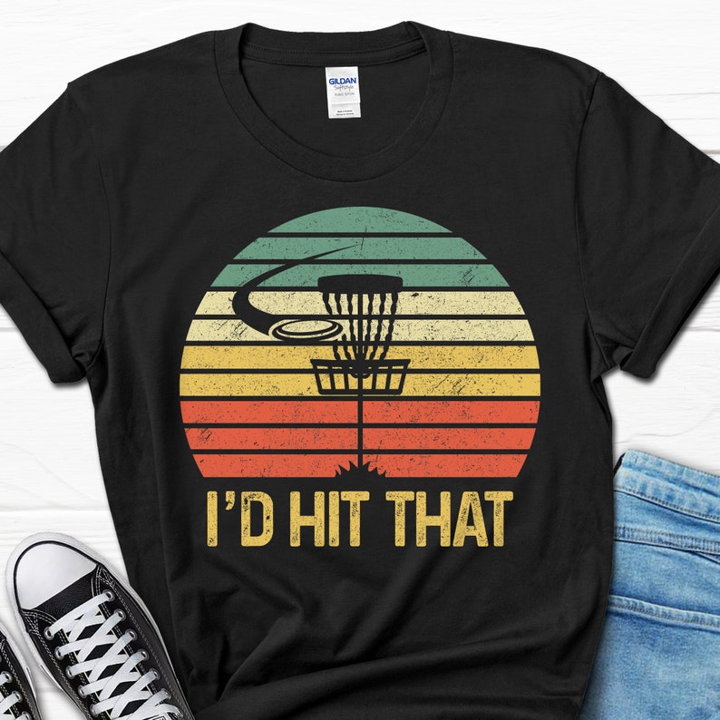 May include: Black t-shirt with a vintage-style graphic of a disc golf basket and the text "I'd Hit That".