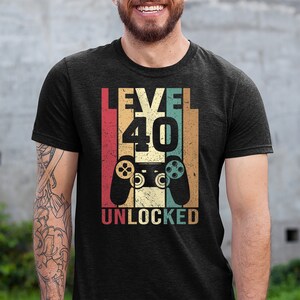 May include: A black t-shirt with a vintage-style graphic that says "Level 40 Unlocked" with a retro video game controller.