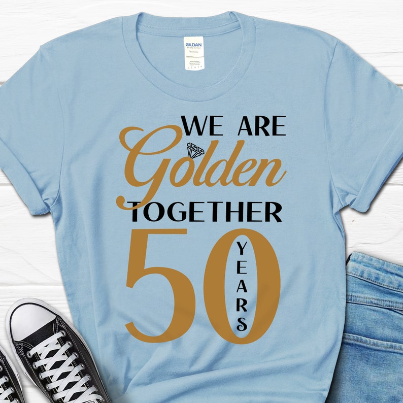 May include: Light blue t-shirt with the text "We are Golden Together 50 Years" in black and gold lettering. The number 50 is large and gold, with the word "Years" vertically stacked inside the number.