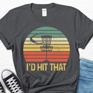 May include: A dark gray t-shirt with a vintage-style graphic of a disc golf basket and the text "I'd Hit That".
