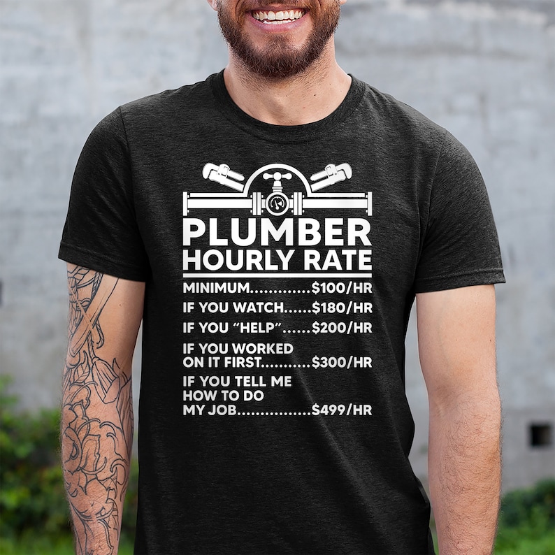 May include: A black t-shirt with a white graphic of a plumber's tools and the text "Plumber Hourly Rate". The graphic includes a pipe, wrench, and valve. The text below the graphic lists different hourly rates for a plumber based on the level of assistance provided. The rates are: $100/hr for minimum, $180/hr for watching, $200/hr for helping, $300/hr for working on it first, and $499/hr for telling the plumber how to do the job.