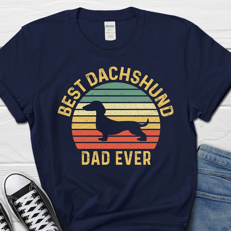 May include: Navy blue t-shirt with a vintage-style graphic of a dachshund and the text "Best Dachshund Dad Ever".
