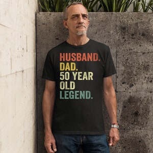 May include: Black t-shirt with a vintage-style graphic that reads "Husband. Dad. 50 Year Old Legend."