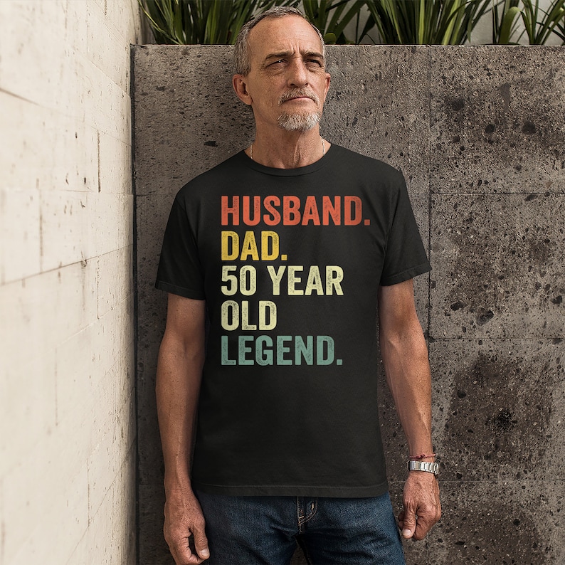 May include: Black t-shirt with a vintage-style graphic that reads "Husband. Dad. 50 Year Old Legend."
