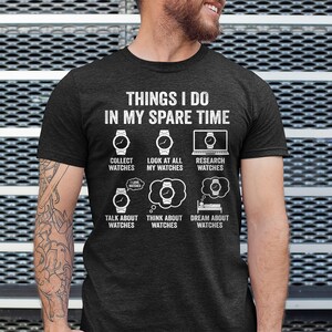May include: Dark gray t-shirt with white text and watch graphics. The text reads "THINGS I DO IN MY SPARE TIME" with illustrations of watches and phrases like "Collect Watches" and "Dream About Watches".