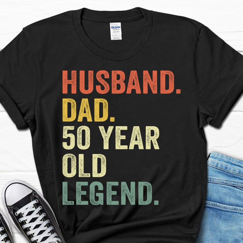 May include: Black t-shirt with a vintage-style graphic that reads "Husband. Dad. 50 Year Old Legend."