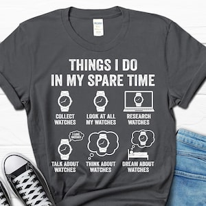 May include: Dark gray t-shirt with white text and watch graphics. The text reads "THINGS I DO IN MY SPARE TIME" with phrases like "Collect Watches" and "Dream About Watches". A fun gift for watch enthusiasts.