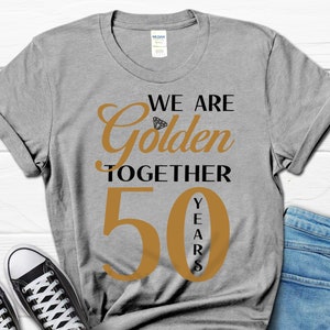 May include: Gray t-shirt with the text "We are Golden Together 50 Years" in black and gold lettering. The number 50 is large and the word "Years" is vertical.