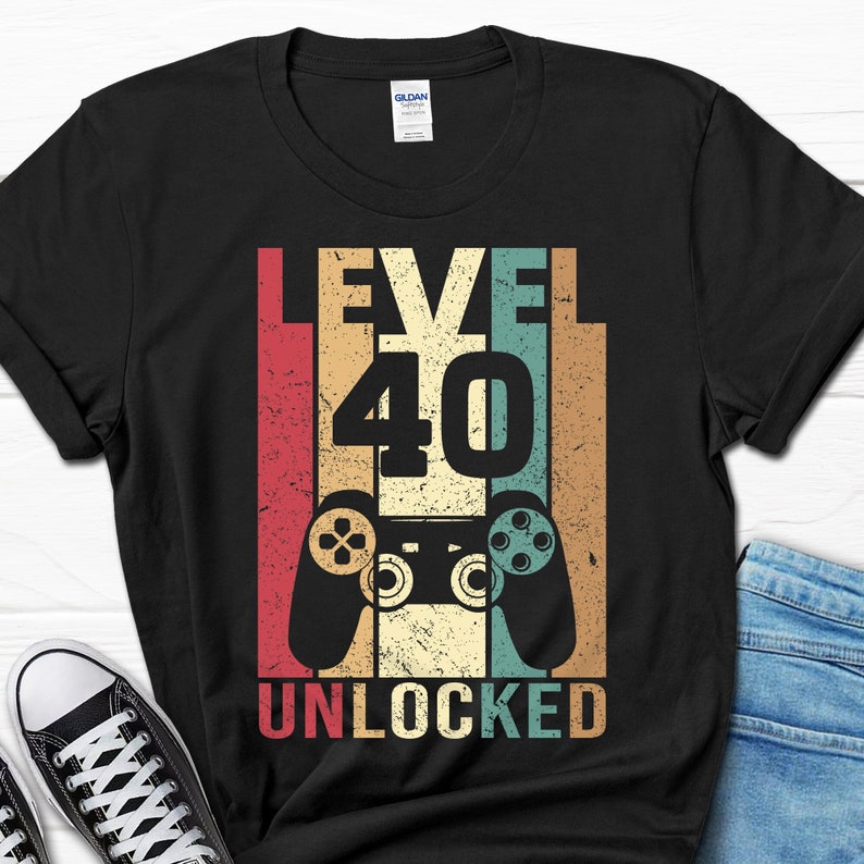 May include: Black t-shirt with a vintage-style graphic that says "Level 40 Unlocked" with a retro video game controller in the center.