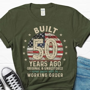May include: Green t-shirt featuring a distressed American flag design with the text "Built 50 Years Ago Original & Unrestored - most parts still in - Working Order".
