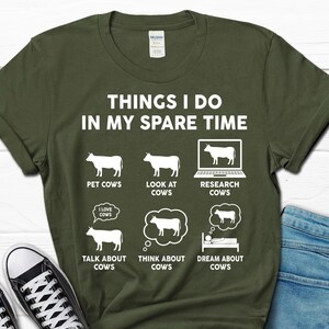 以下が含まれることがあります： 「Things I do in my spare time」というテキストと、牛に関連する活動のリストが書かれた緑色のTシャツ。リストには、「牛をなでる」、「牛を見る」、「牛を調べる」、「牛について話す」、「牛について考える」、「牛の夢を見る」などが含まれています。