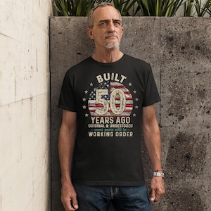 May include: A black t-shirt with a vintage American flag design and the text "BUILT 50 YEARS AGO ORIGINAL & UNRESTORED - most parts still in - WORKING ORDER".
