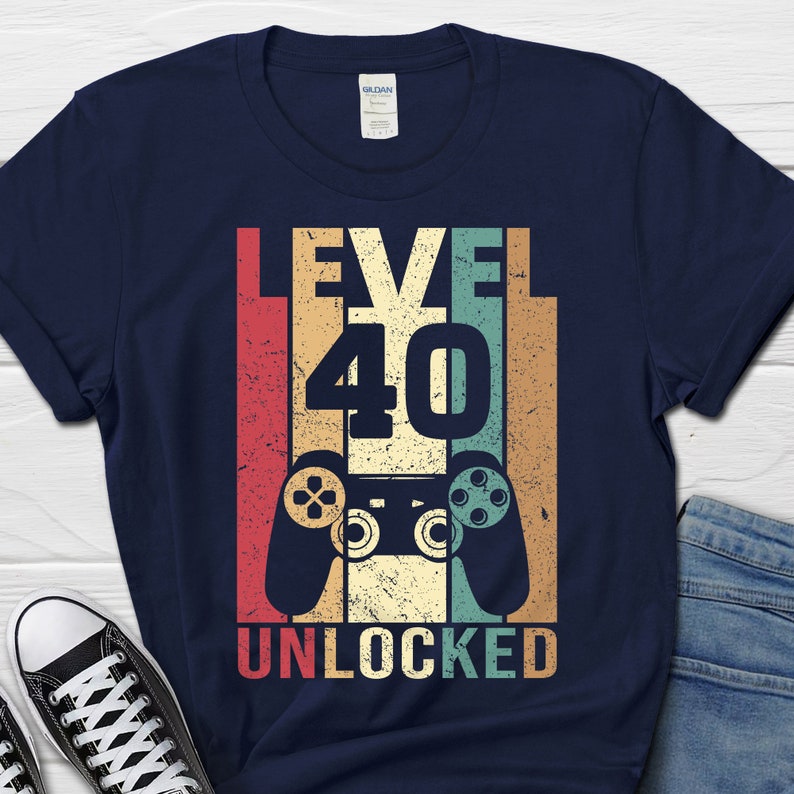 May include: A navy blue t-shirt with a vintage-style graphic that says "Level 40 Unlocked" with a retro video game controller.