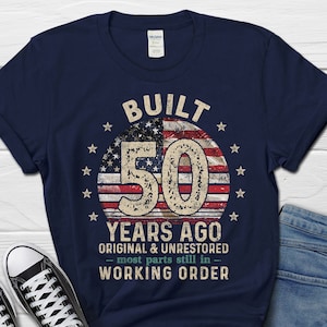 May include: Navy blue t-shirt featuring a distressed American flag design and the text "BUILT 50 YEARS AGO ORIGINAL & UNRESTORED - most parts still in - WORKING ORDER".