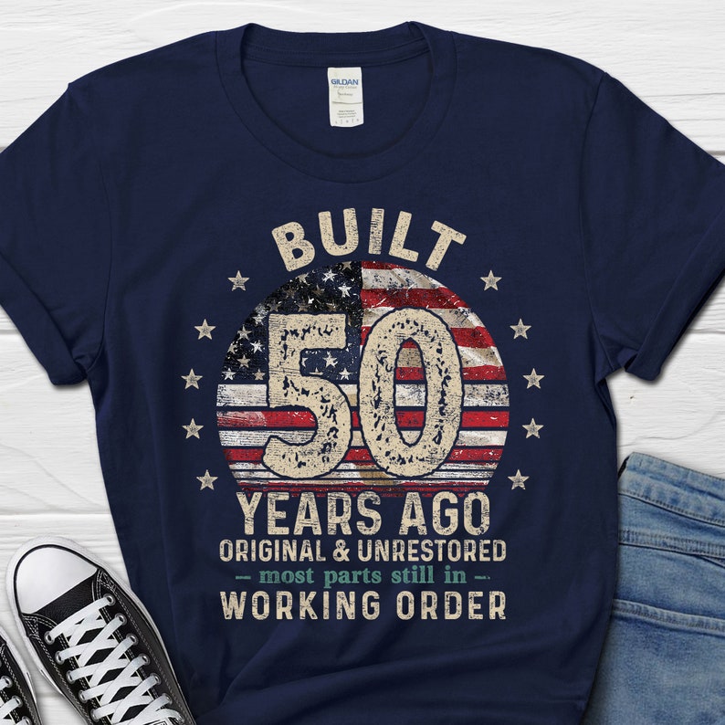 May include: Navy blue t-shirt featuring a distressed American flag design and the text "BUILT 50 YEARS AGO ORIGINAL & UNRESTORED - most parts still in - WORKING ORDER".