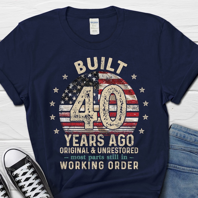 May include: Navy blue t-shirt with a distressed American flag design and the text "BUILT 40 YEARS AGO ORIGINAL & UNRESTORED - most parts still in - WORKING ORDER".