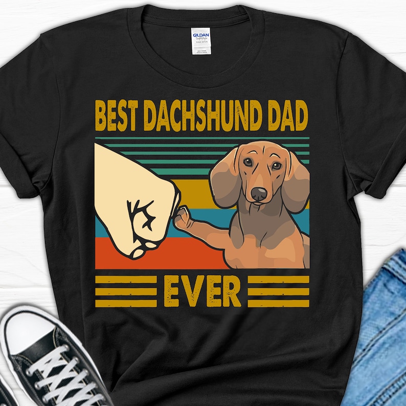 May include: Black t-shirt with a vintage-style graphic of a dachshund dog with the text "Best Dachshund Dad Ever".