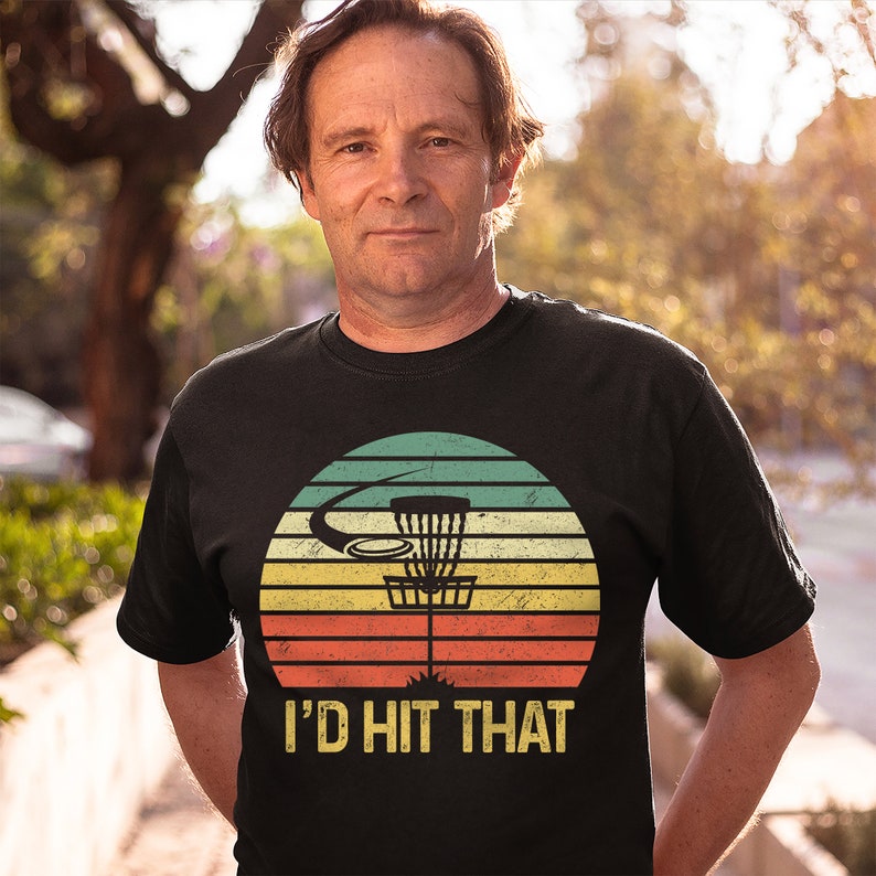May include: A black t-shirt with a vintage-style graphic of a disc golf basket and the text "I'd Hit That".