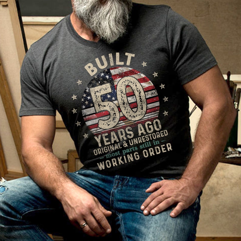 May include: A grey t-shirt with a vintage American flag design and the text "Built 50 Years Ago Original & Unrestored - most parts still in working order".