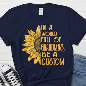 May include: A navy blue t-shirt featuring a sunflower graphic and the text "In a world full of grandmas, be a custom".