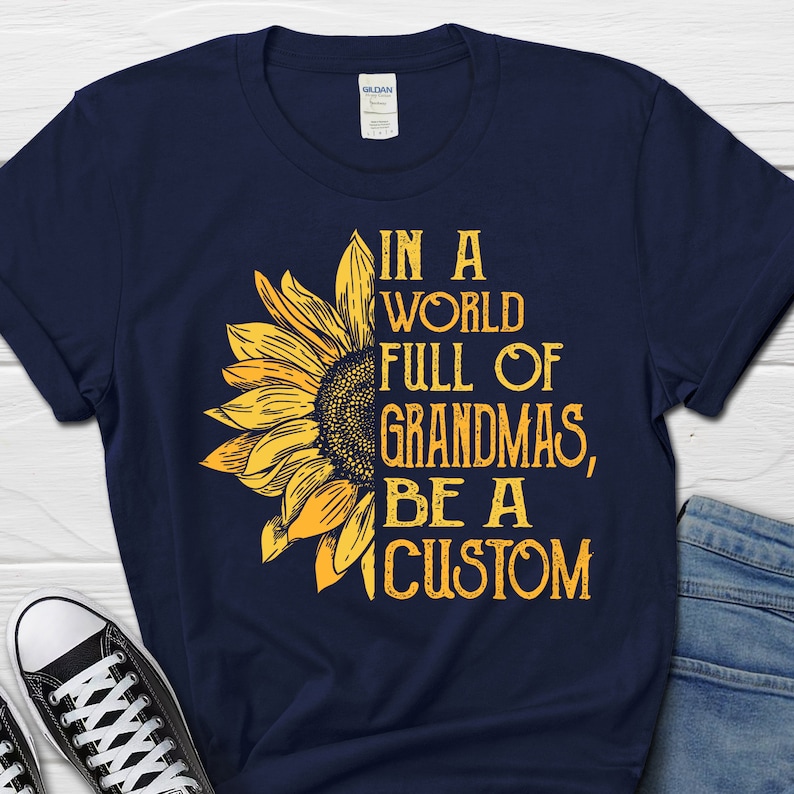 May include: A navy blue t-shirt featuring a sunflower graphic and the text "In a world full of grandmas, be a custom".