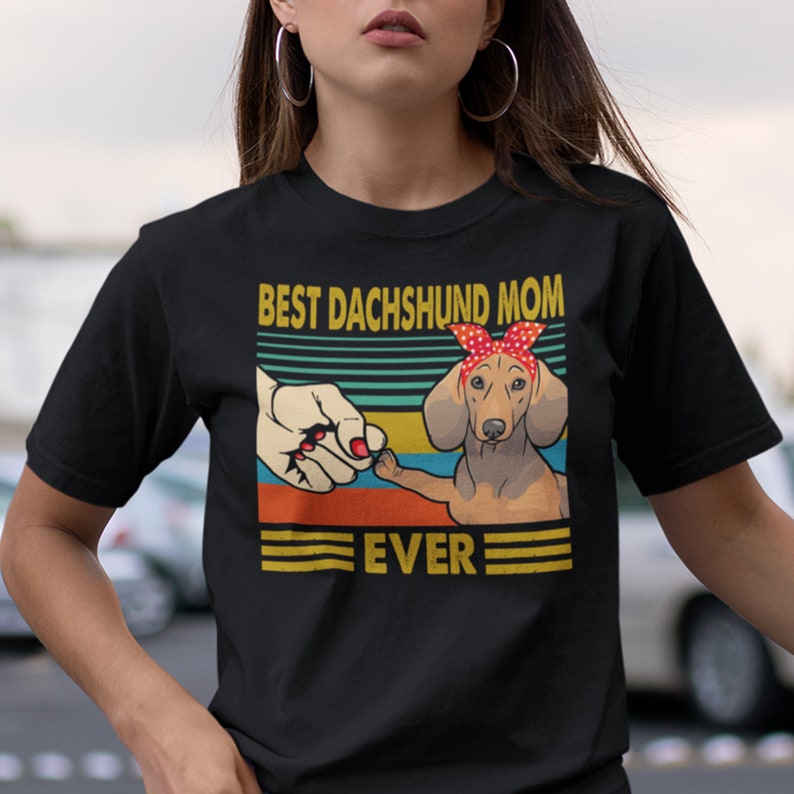 May include: Black t-shirt with a vintage-style graphic of a dachshund wearing a red bandana. The graphic says "Best Dachshund Mom Ever".