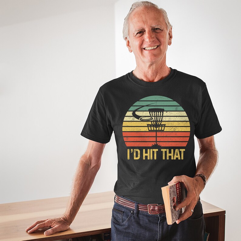 May include: A black t-shirt with a vintage-style graphic of a disc golf basket and the text "I'd hit that".