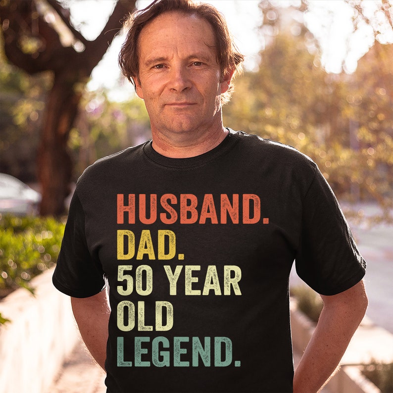 May include: A black t-shirt with a vintage-style graphic that reads "Husband. Dad. 50 Year Old Legend."