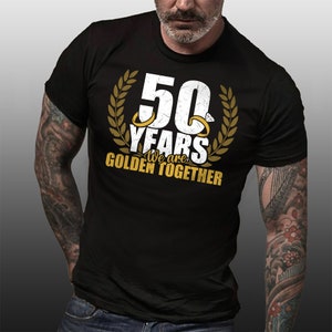 May include: Black t-shirt with a white graphic that says "50 Years We are Golden Together" with two gold rings and a laurel wreath.