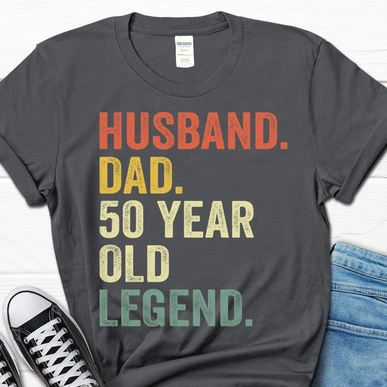 May include: A dark gray t-shirt with the text "Husband. Dad. 50 Year Old Legend." in a vintage style font.