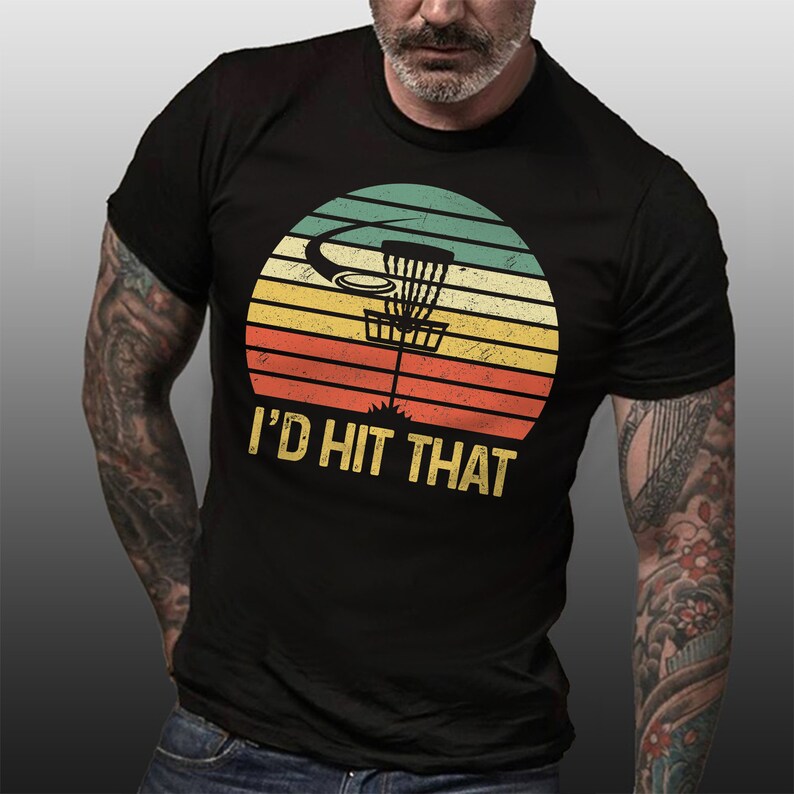 May include: A black t-shirt with a vintage-style graphic of a disc golf basket and the text "I'd Hit That".