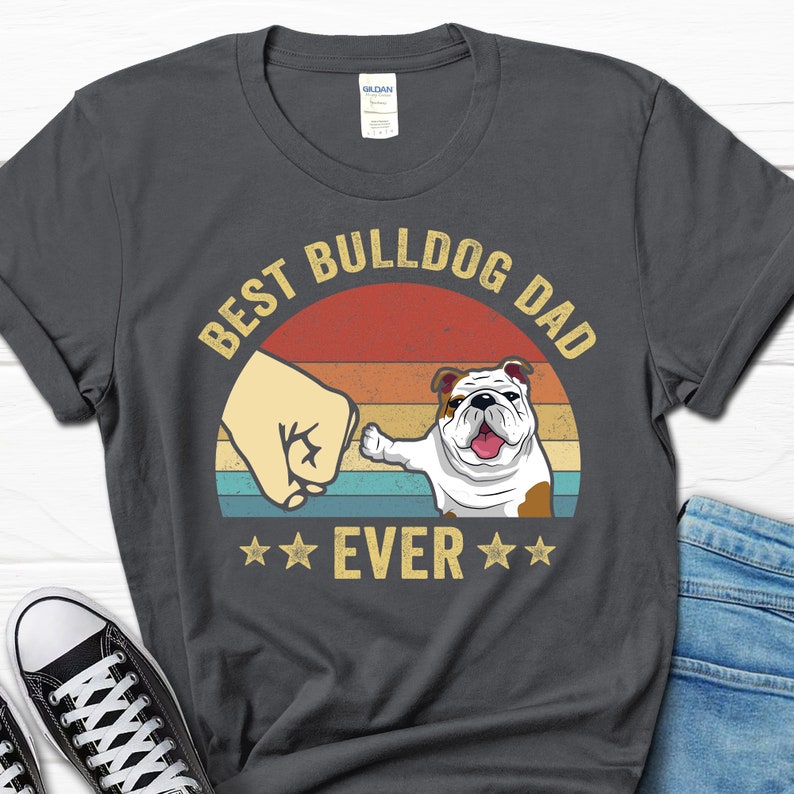 May include: A dark gray t-shirt with a vintage-style graphic that says "Best Bulldog Dad Ever" with a cartoon bulldog and a fist bump.