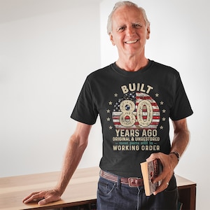 May include: Black t-shirt with a distressed American flag design and the text "BUILT 80 YEARS AGO ORIGINAL & UNRESTORED - most parts still in - WORKING ORDER".